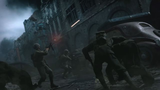 Image of Call of Duty: WWII, there are characters dressed in army uniform on screen defending soldiers on a debris filled street. Black smoke tunnels into the air with gunfire piercing the sky.
