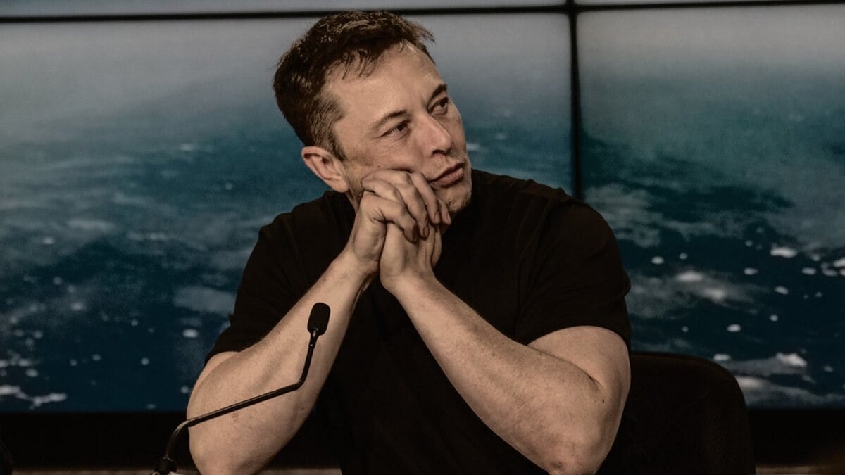 Elon Musk holding his hands together at a press conference.
