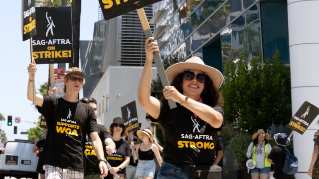 SAG-AFTRA members march on the street with strike banners and signs