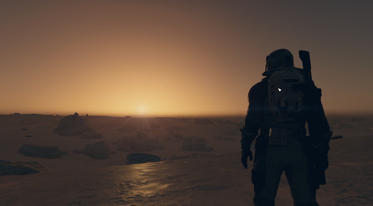 An explorer wearing a space suit stands looking at the horizon as the sun sets on an icy planet in Starfield.