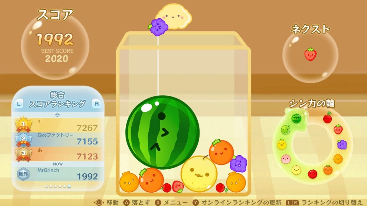 Suika Game where a bunch of grapes is being dropped on top other fruits