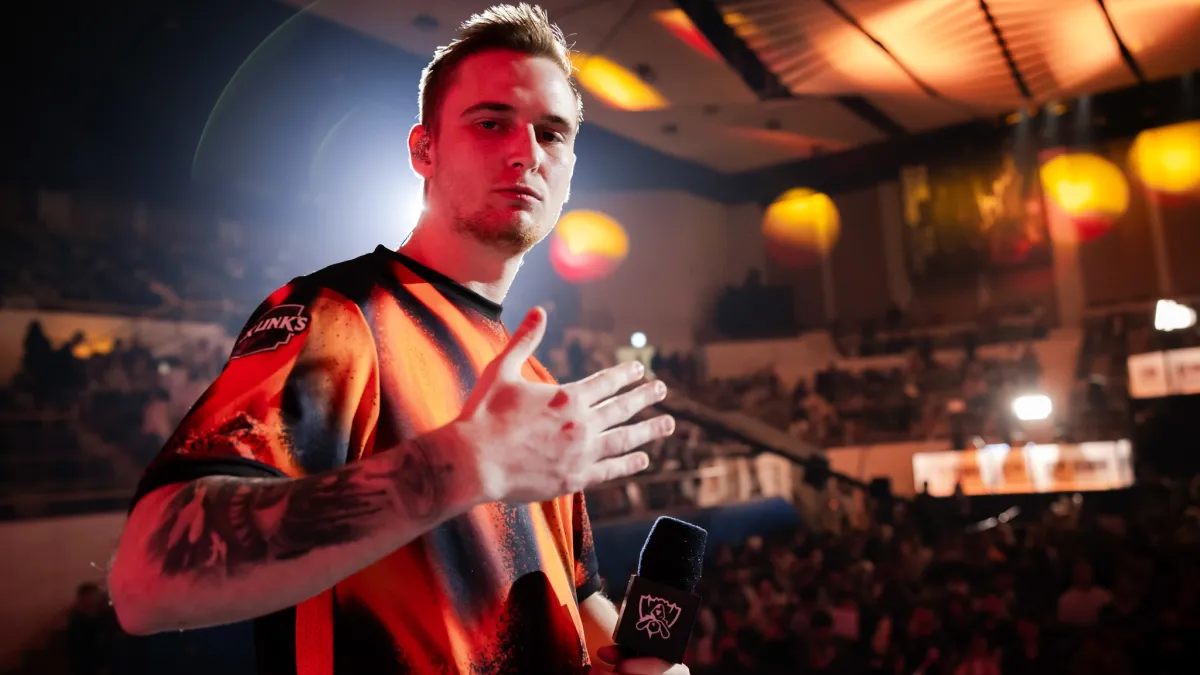 Fnatic's Humanoid holding a microphone and waving at Worlds 2023 Swiss stage.