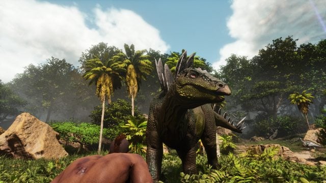 A player hiding from a stegosaur in Ark: Survival Ascended