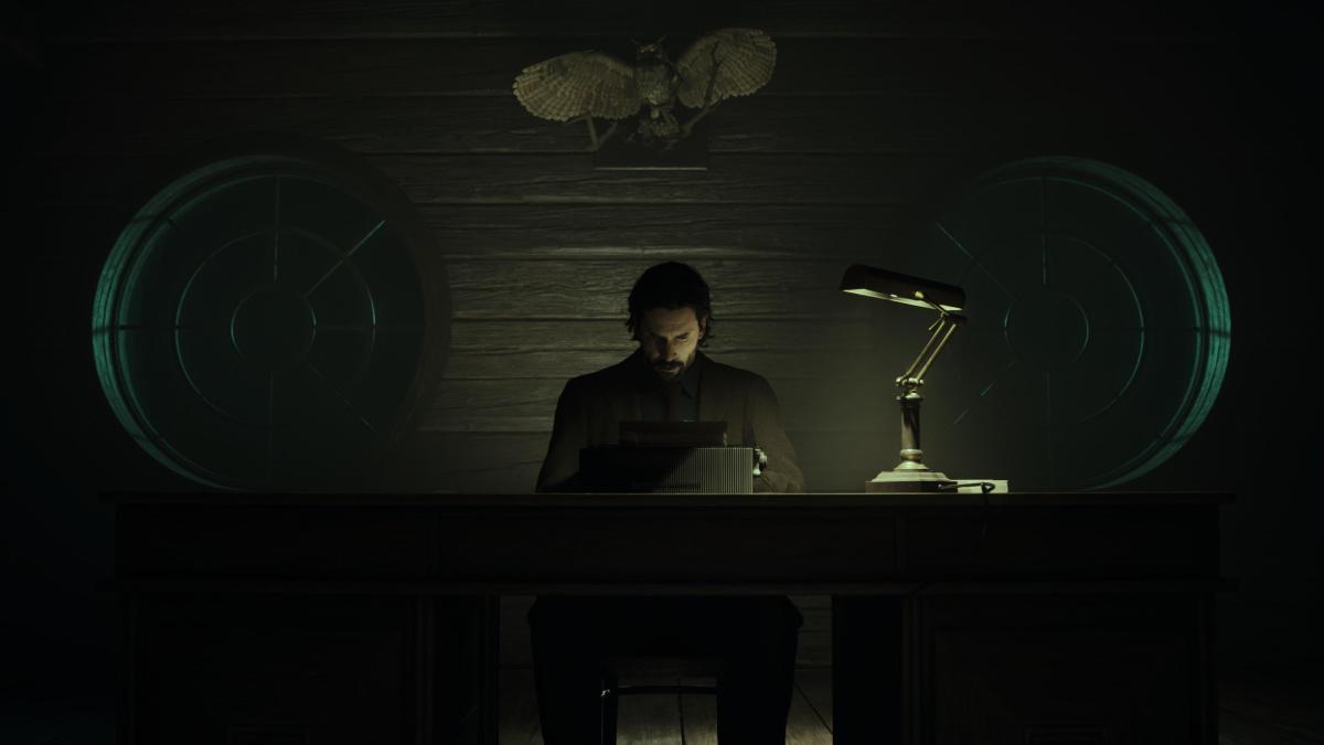 Alan Wake typing at his typewriter in a dark room