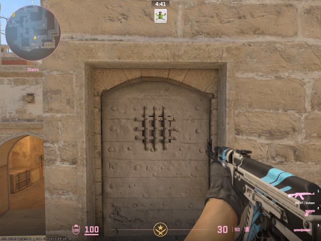 The classic viewmodel in CS2 on mirage with an ak47 pointed at a door