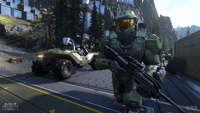 Master Chief runs forward with a Battle Rifle in his hands, accompanied by three other Spartans in a Warthog.