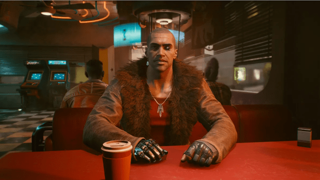 River Ward sits at a red table in a diner in the Cyberpunk 2077 mission "The Hunt". 