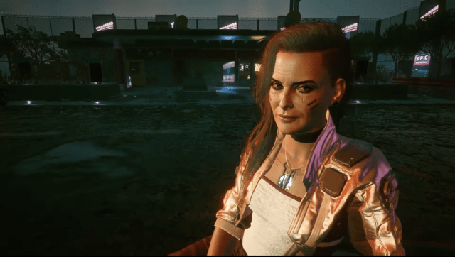 Rogue from Cyberpunk 2077 looks at the player in an abandoned Drive-In theater.