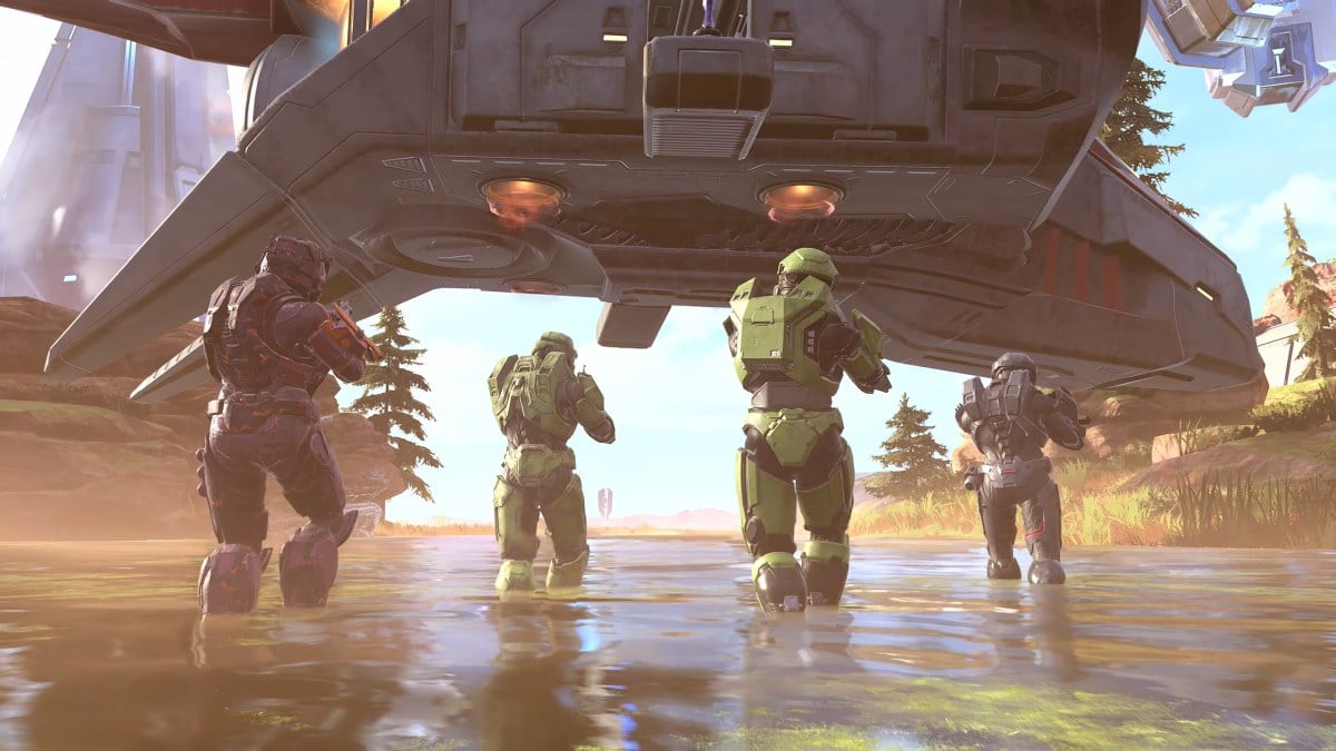 Four Spartans are walking through the water toward a Covenant Phantom that is coming down to land on a desert plateau.