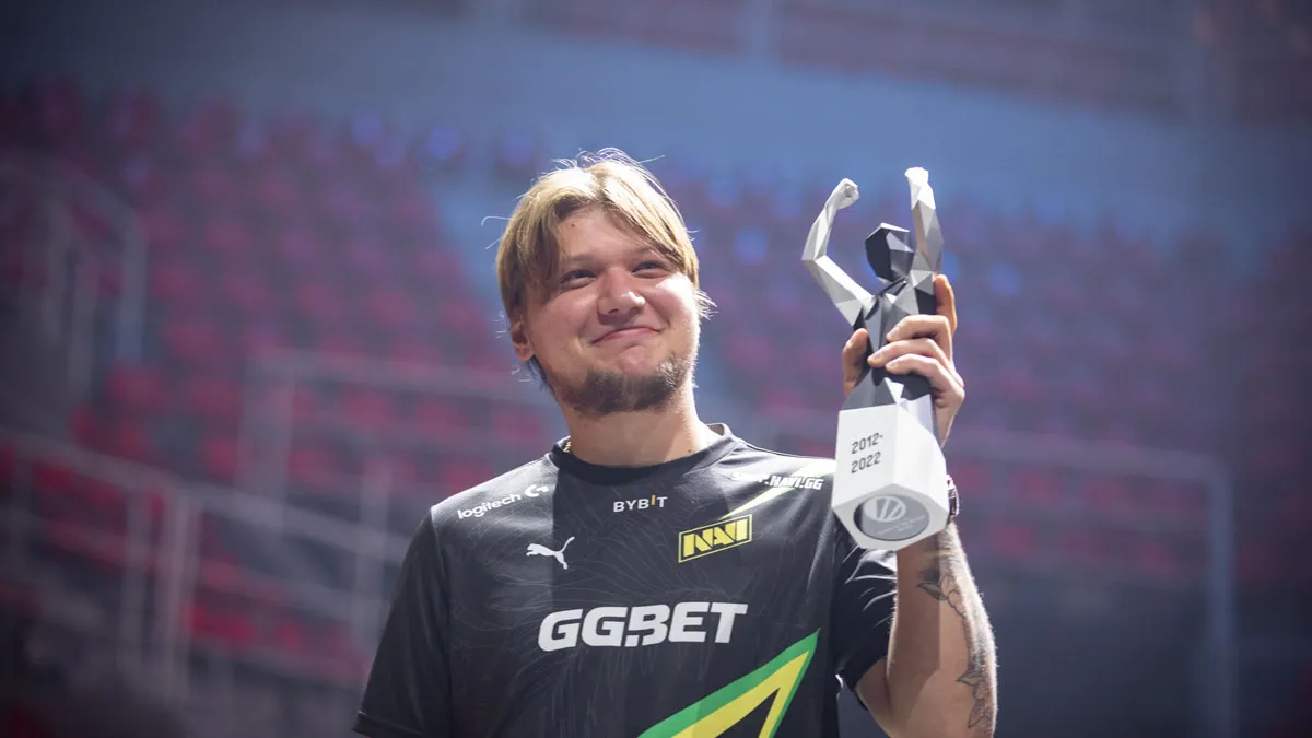 S1mple, a Counter-Strike player, wearing a NAVI jersey and lifting a trophy in a stadium.