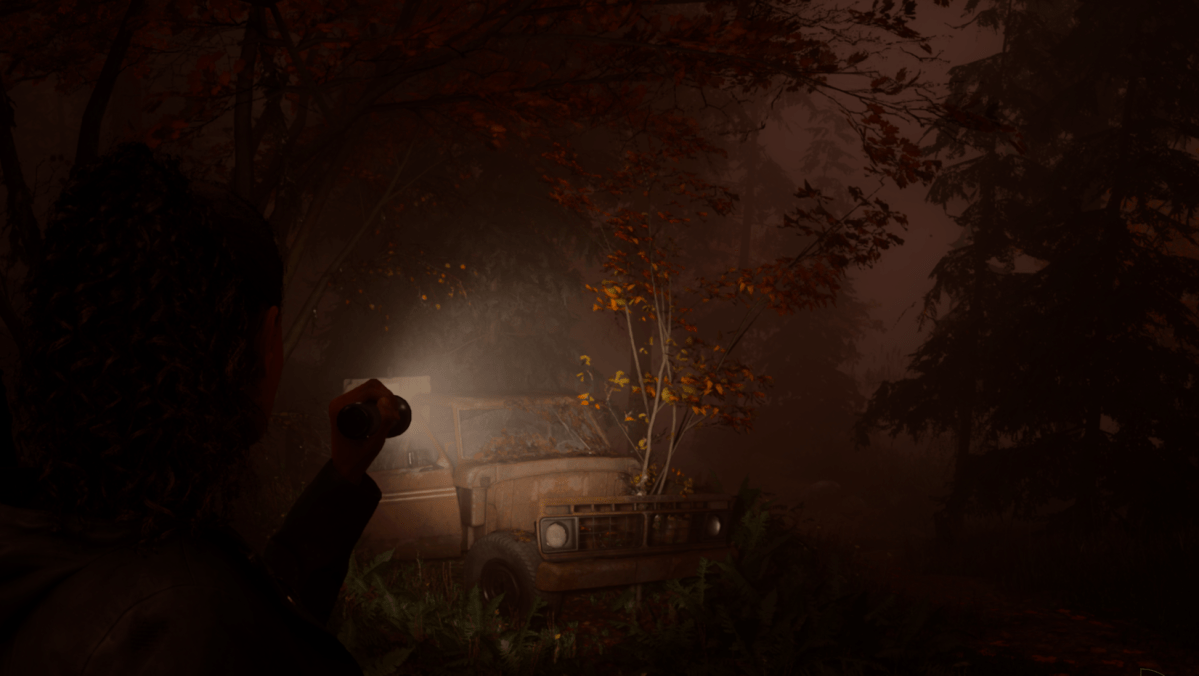 Saga pointing a flashlight at a red pickup truck in the woods in Alan Wake 2.