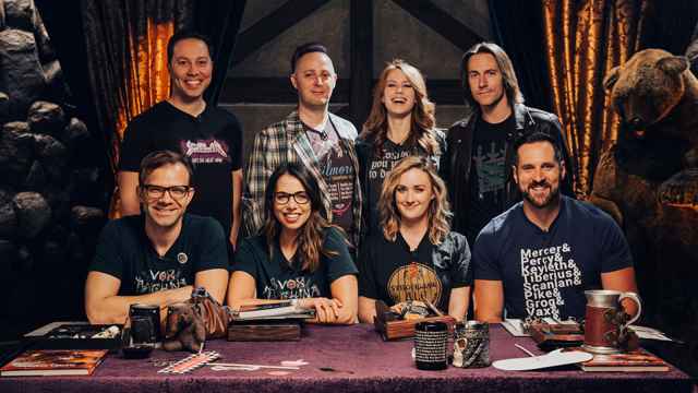Photo of Critical Role's entire cast. Half of the crew is sit and the other half is standing up.