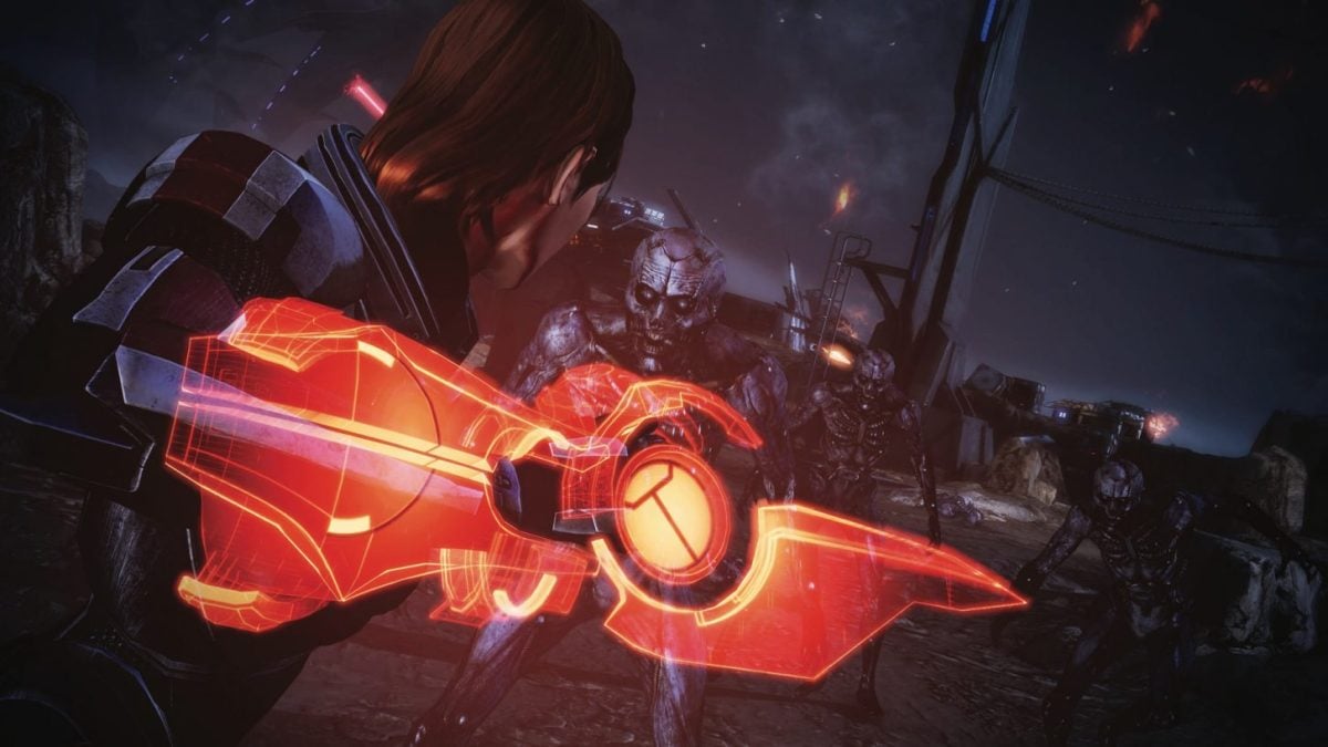 A screenshot from Mass Effect showing Shepard holding her orange omnitool as she fights husks.