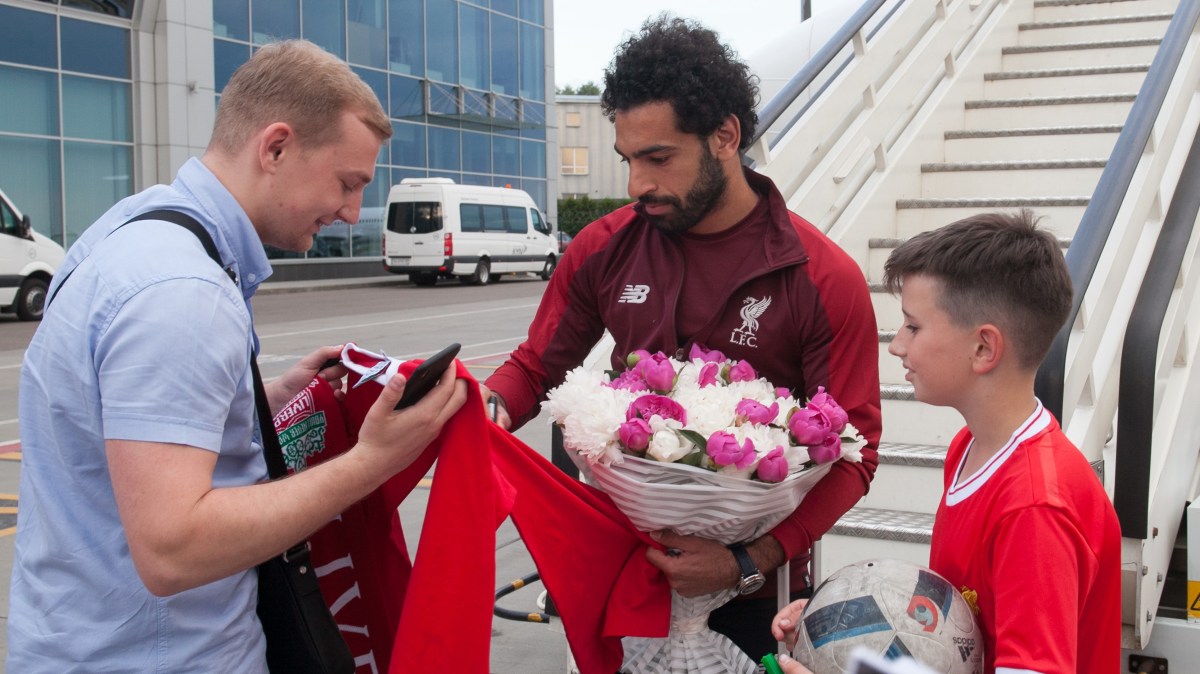 Photo taken of soccer Mohamed Salah signing a Liverpool's fan jersey.