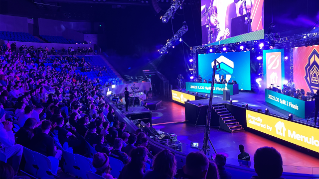 A crowd at Dreamhack Melbourne 2022 sits in dim blue light of the finals. The Chiefs are on stage.