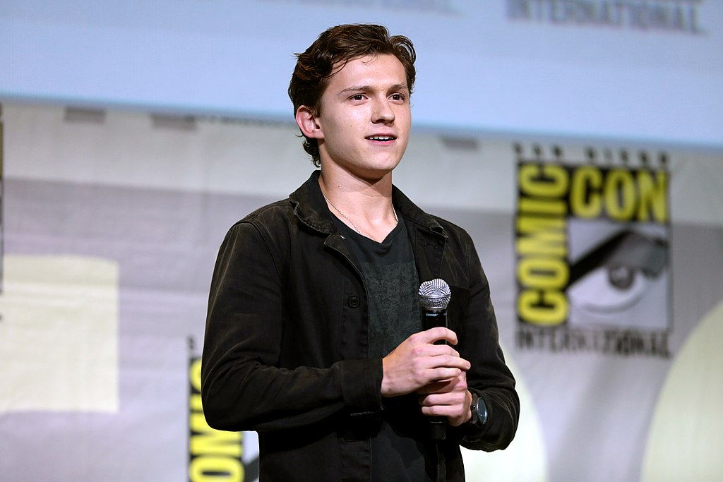 Tom Holland holding a microphone and speaking at a Comicon convention.