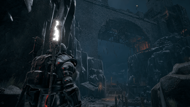 A heavily armored man with a stone staff looks at a long hanging bridge in Remnant 2.