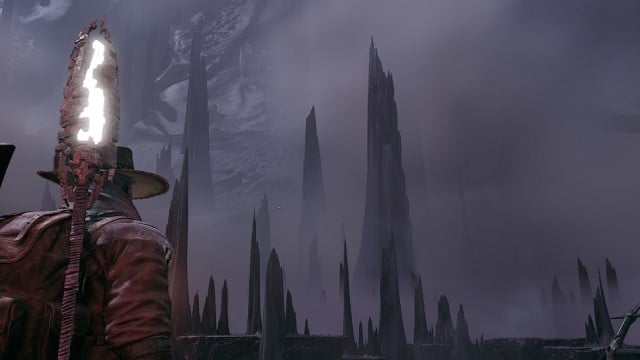 A man in a small hat and staff looks to the sharp mountain peaks of Remnant 2 N'Erud.