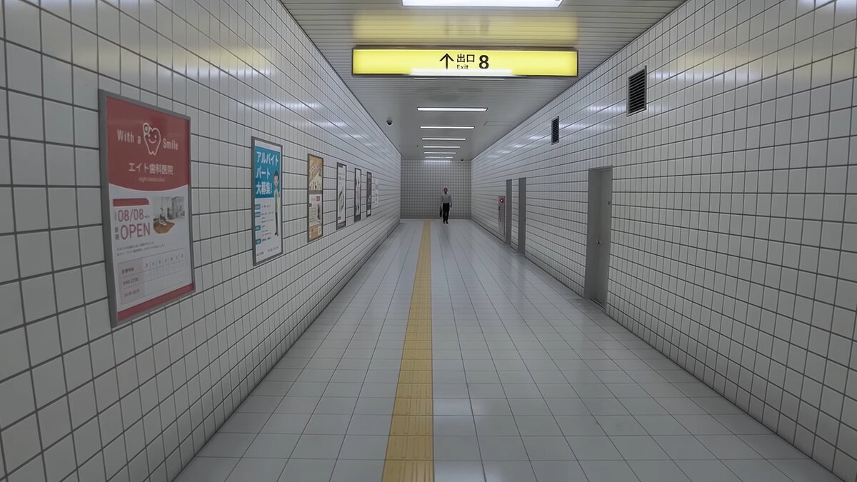 The Exit 8 subway corridor with character walking in the distance