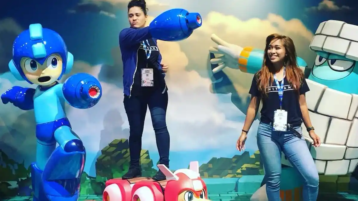 Two girls posing next to video game character