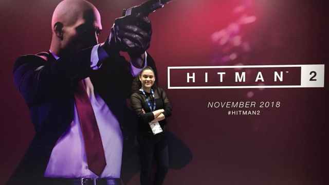 Girl wearing black standing in front of a Hitman 2 poster