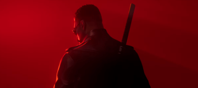 Blade standing in the red background with his back turned to the camera.