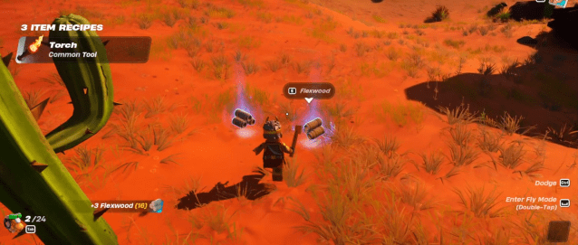 A LEGO Fortnite character looks at some Flexwood on the ground in a desert.