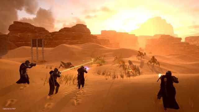 Four players move through a deserted biome in Helldivers 2
