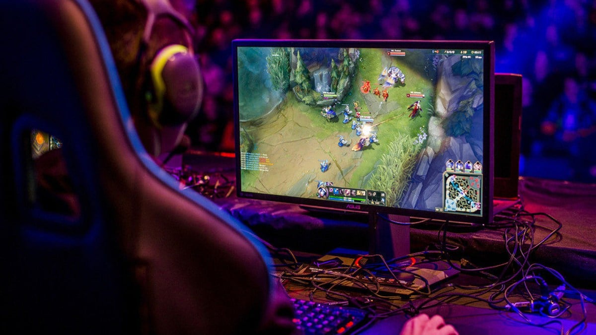 A gamer in a high-backed seat plays a game of League of Legends in front of a blurry crowd