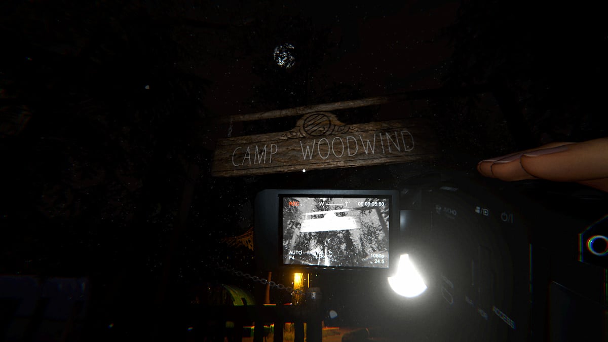 A player holding a camera recording as they approach the wooden Camp Woodwind sign hanging over the entrance in Phasmophobia.