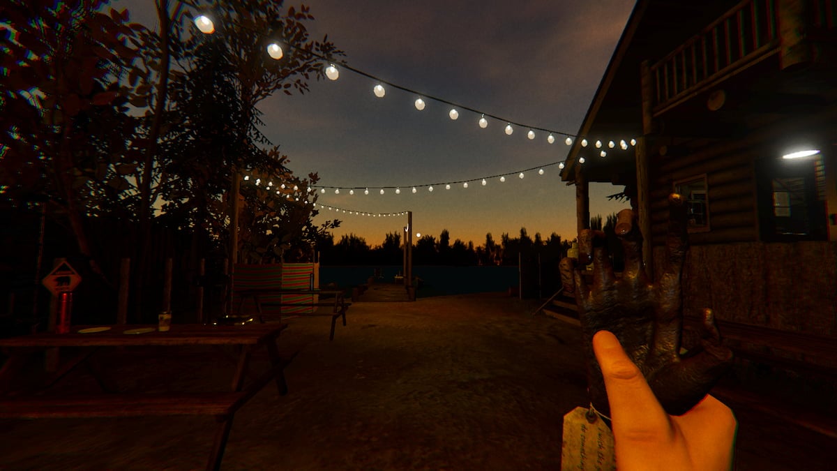 Holding a Monkey Paw while standing under some lit string lights at Male Lodge Campsite in Phasmophobia.