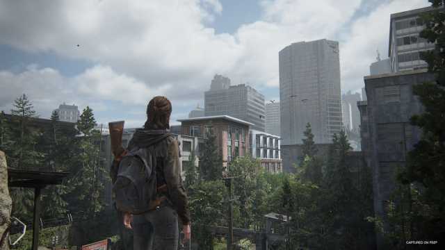 Ellie looks into an set of buildings taken by nature in The Last of Us 2.