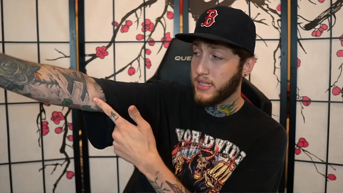 FaZe Banks points at his FaZe tattoo on his arm.