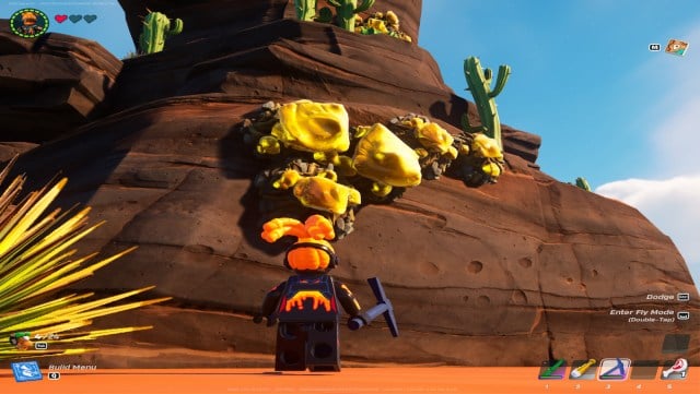 A screenshot from Lego Fortnite showing the player looking at Rough Amber, a yellow and black substance on a giant rock.