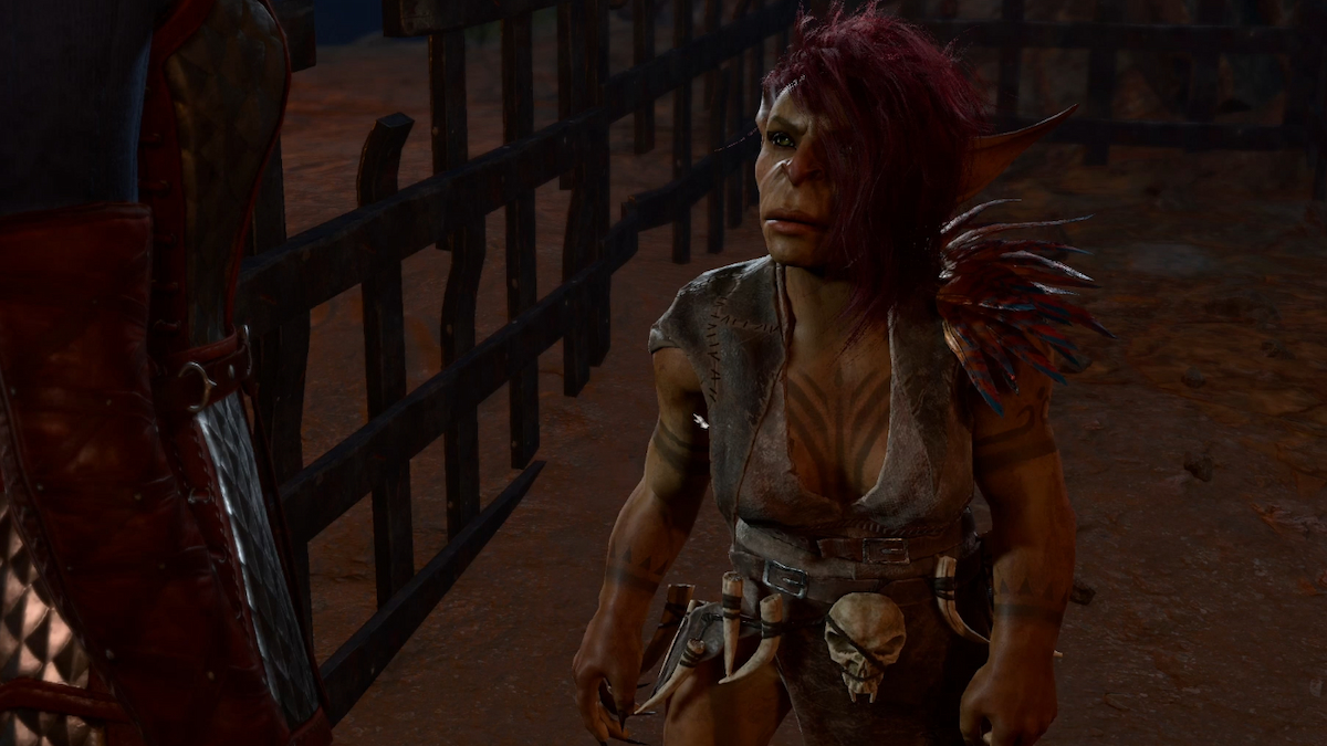 A red-haired goblin with tattoos on her chest stands in front of an open cell in Baldur's Gate 3.
