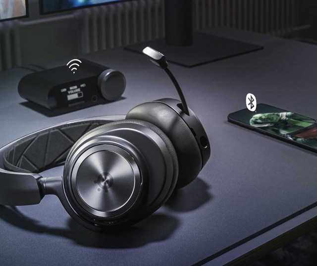 SteelSeries Arctis Nova Pro Wireless on a table next to a phone and a router