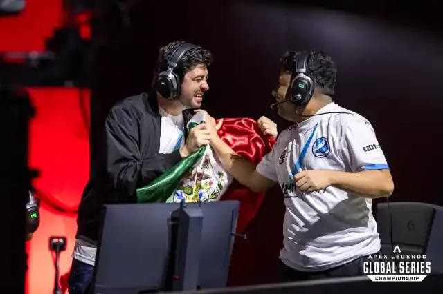 Two Apex pro players grasp a Mexican flag at the 2023 Apex Legends Global Series Championship.