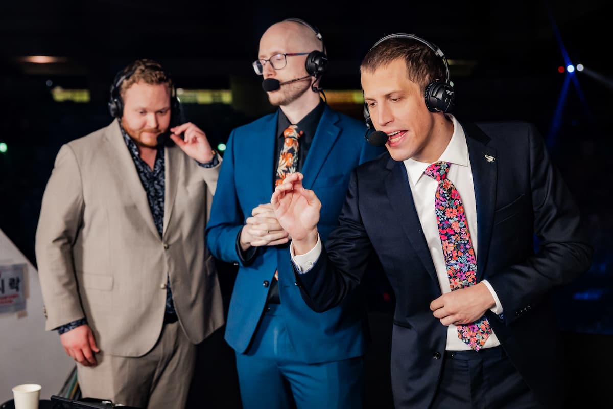 CaptainFlowers casting at Worlds 2023, taking into his headset and making a gesture with his hands.