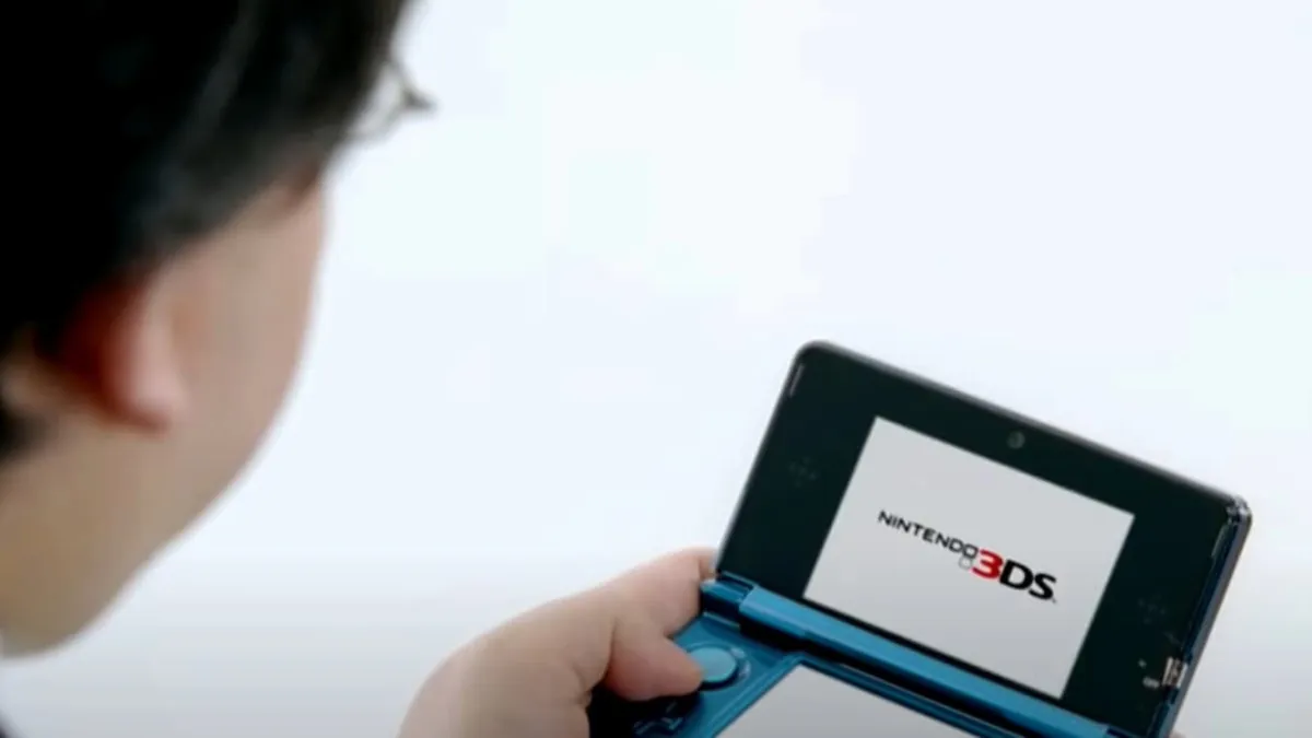 Satoru Iwata looking at a Nintendo 3DS.