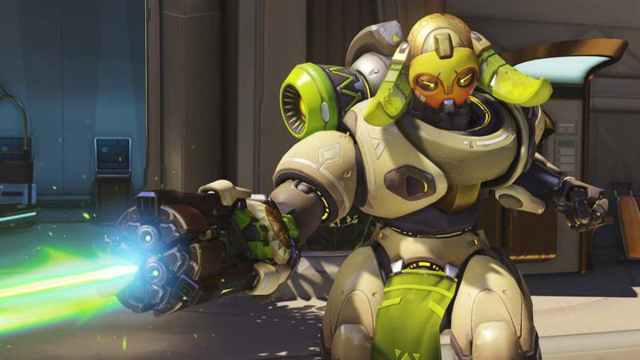 Overwatch 2 hero Orisa firing her primary weapon from her arm in an aggressive stance.