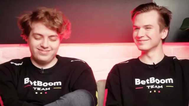Pure, a Dota 2 player, is pictured sitting next to his teammate smiling.