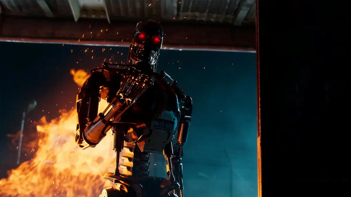 A Terminator closes its fist as a fire rages in the background.