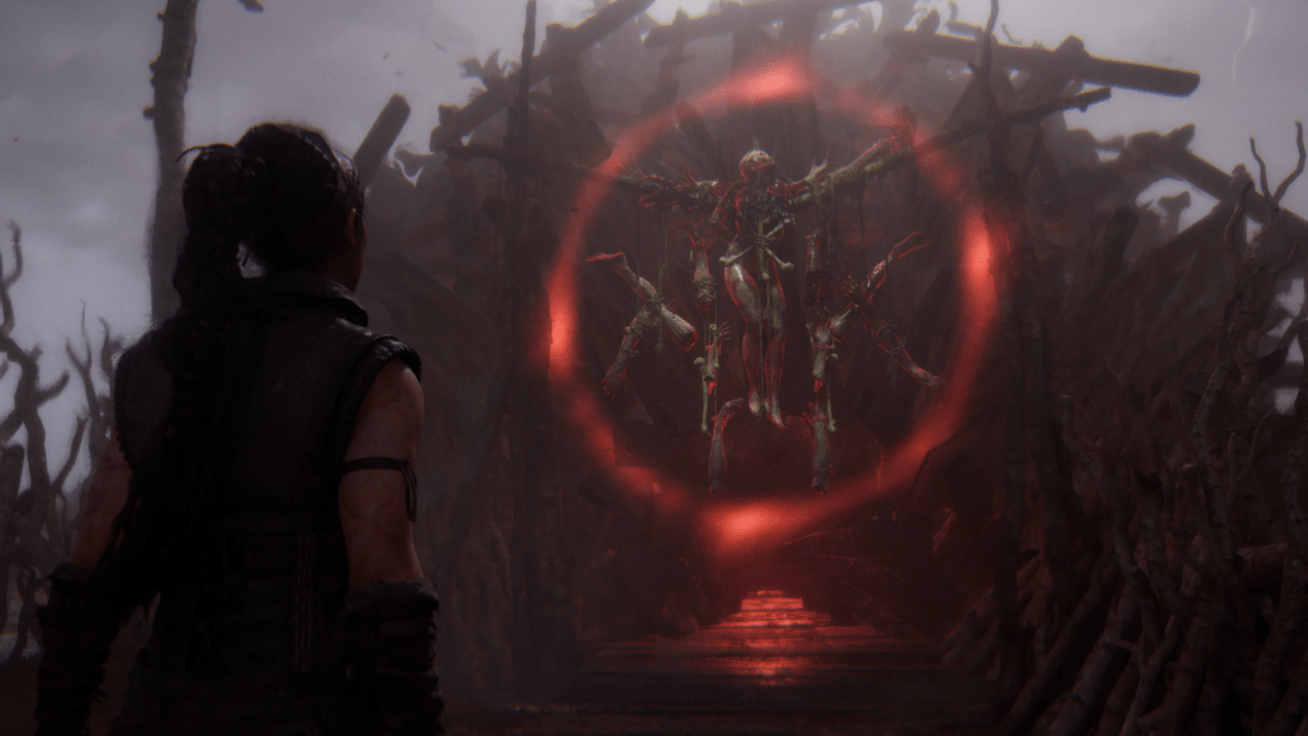 Senua looks at a red ring around a symbol on a gate