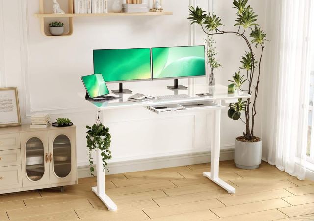 Innovar Glass Gaming Desk with two green monitors on top, in a white room