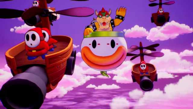 Bowser in a flying clown face, red and white minions fly in ships with canons nearby