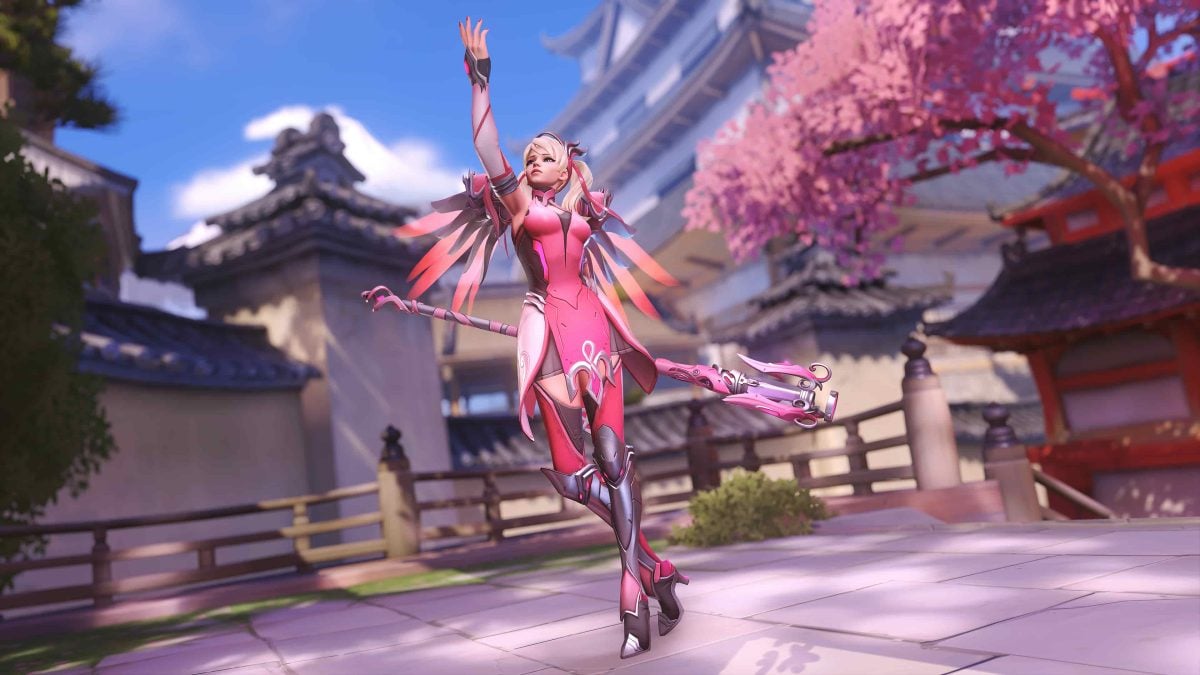 Mercy raises her arm to the sky with her staff held behind her.
