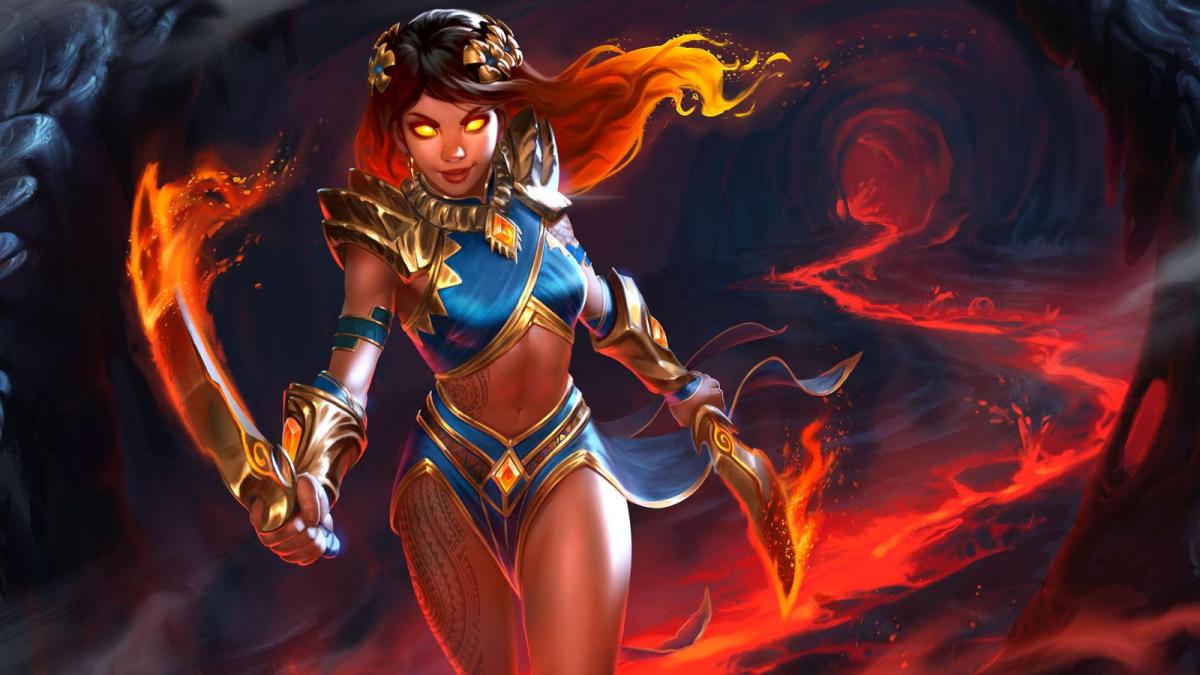 A Smite 2 goddesses walks towards the front of the image with two burning blades. She is standing aboving a lava pit in a cave.