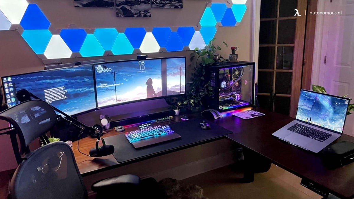 A PC setup with several screens on a desk as well as a laptop to the side