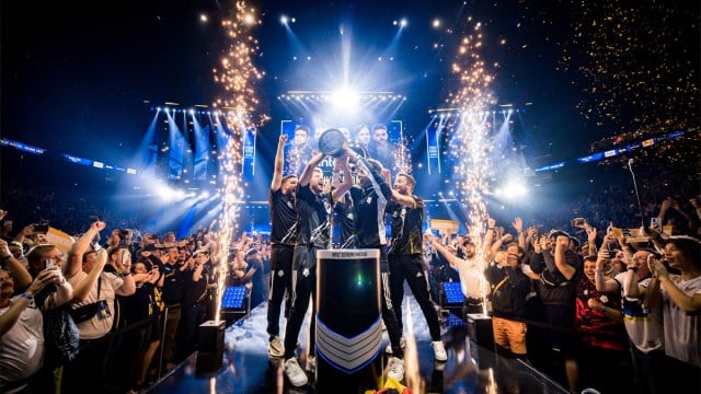 G2 Esports standing on-stage and lifting the IEM Cologne trophy in 2023 as the crowd cheers.