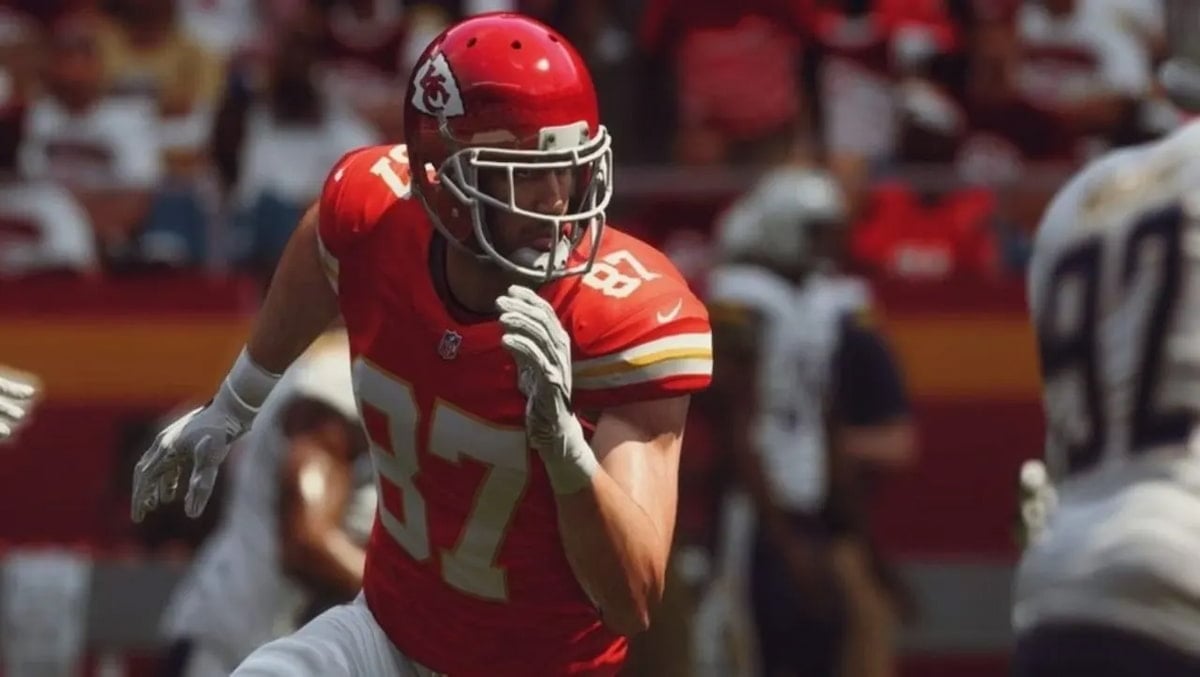 Travis Kelce in Madden, a football player in a red uniform running with fans in the background.
